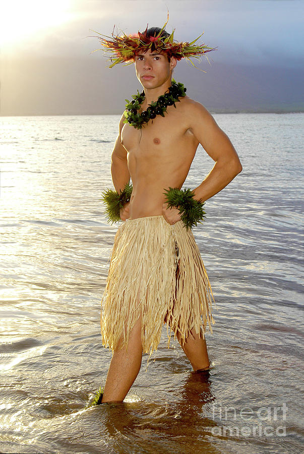 Handsome male hula dancer stands in the water as the sun sets. Photograph by Gunther Allen