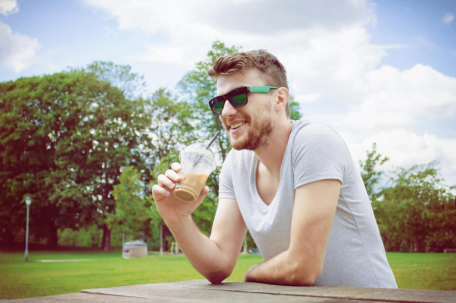 Handsome man drinking coffee in park Photograph by Emapoket