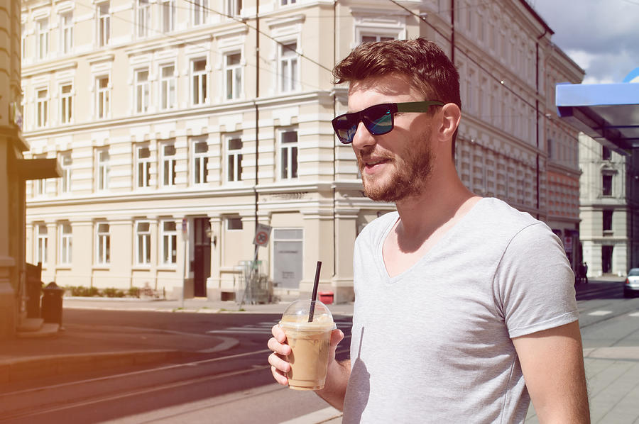 Handsome man drinking coffee on street Photograph by Emapoket