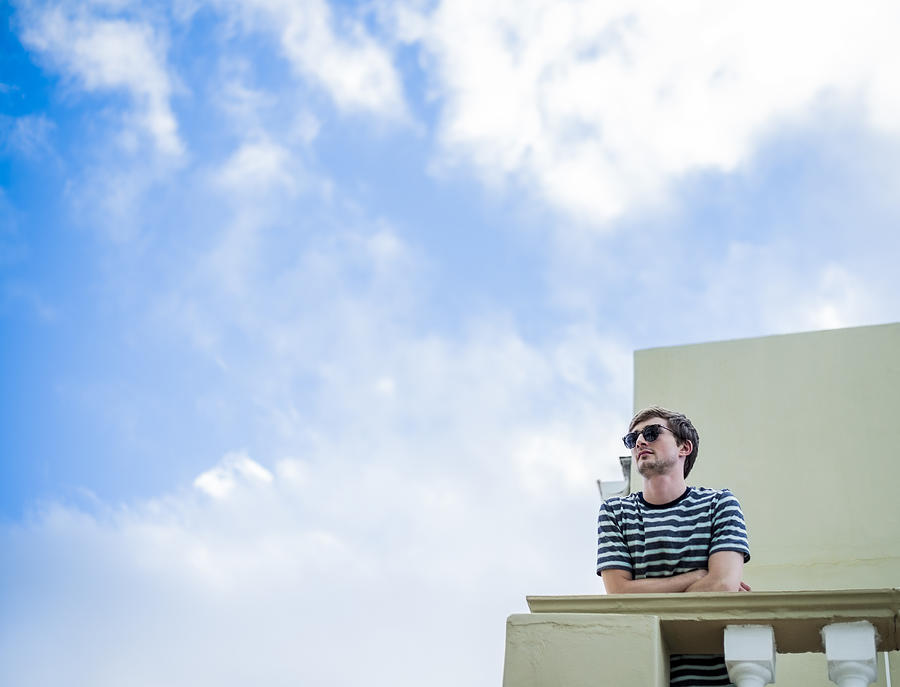 Handsome man standing in balcony against sky Photograph by Portra Images