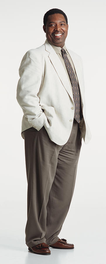 Handsome Middle Aged African American Man Dressed In A Light Blazer And Brown Pants Looking Into The Camera With His Hands In His Pockets Photograph by Photodisc