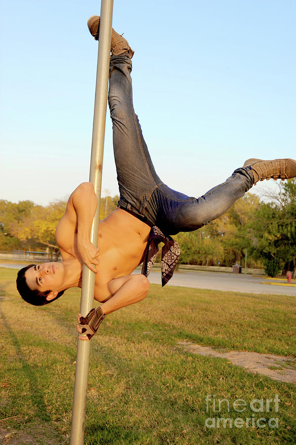 Handsome young hispanic man shows off some pole dance moves Photograph by Gunther Allen