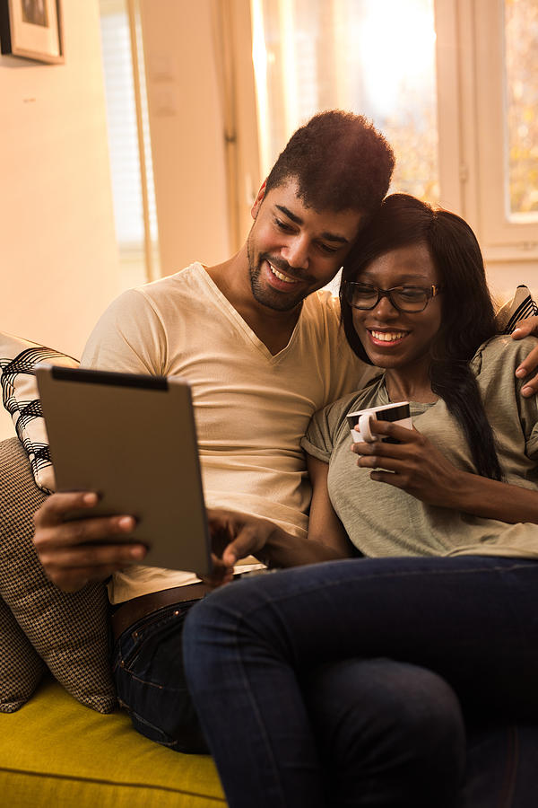 Happy African American couple in love surfing the net on a touchpad. Photograph by Skynesher