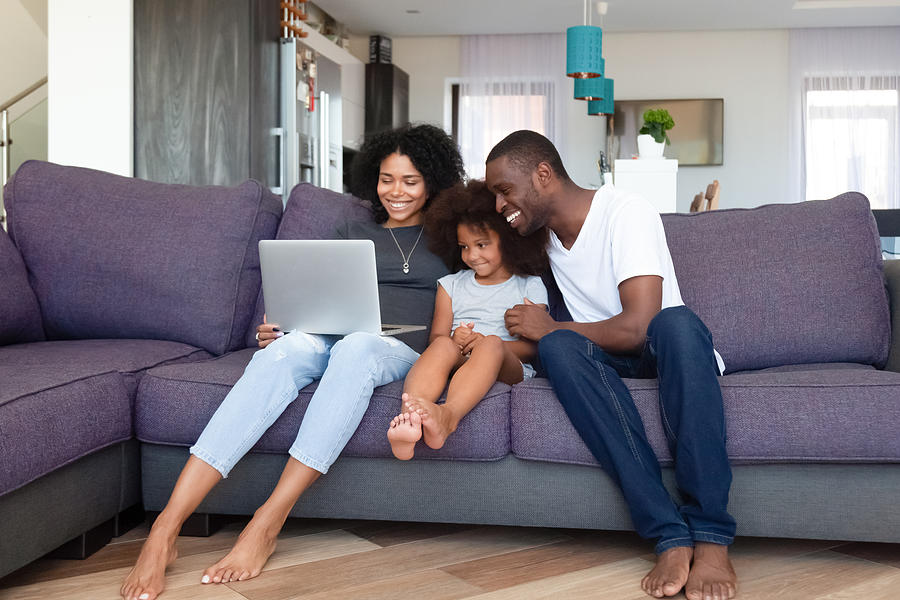 Happy African American family with daughter using laptop at home Photograph by Fizkes