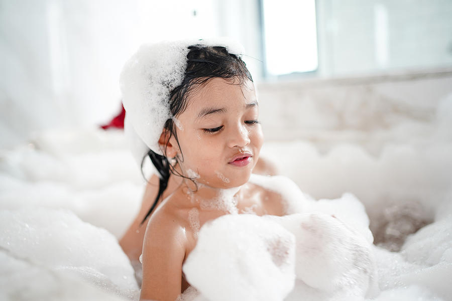 Happy Asian kid bathing concept. adorable girl in bathtub with fluffy soap bubble. Photograph by Narisara Nami
