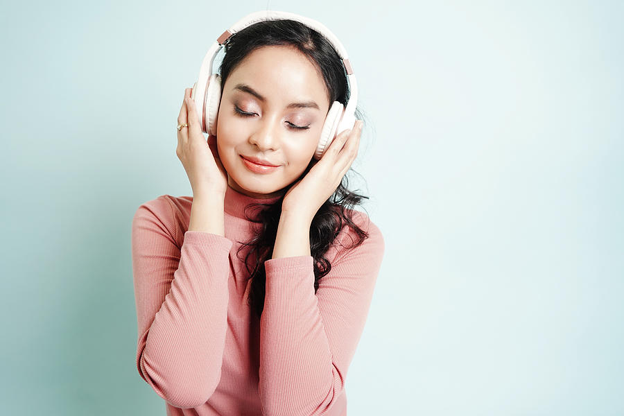 Happy Asian teenage girl listen the music song in wireless headphone from mp3 player technology. relaxation and music lover concept. Photograph by Narisara Nami
