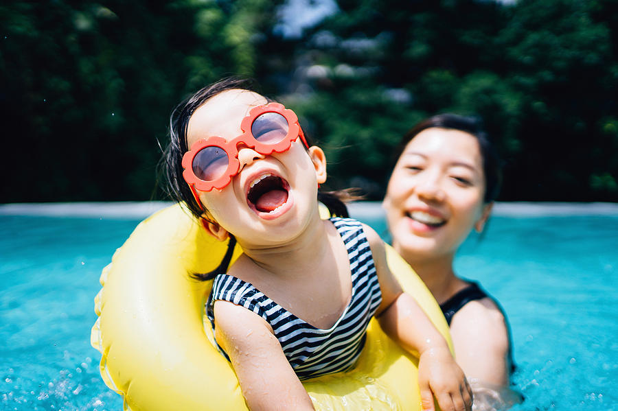 Happy Asian toddler girl with sunglasses smiling joyfully and enjoying family bonding time with mother having fun in the swimming pool in summer Photograph by D3sign