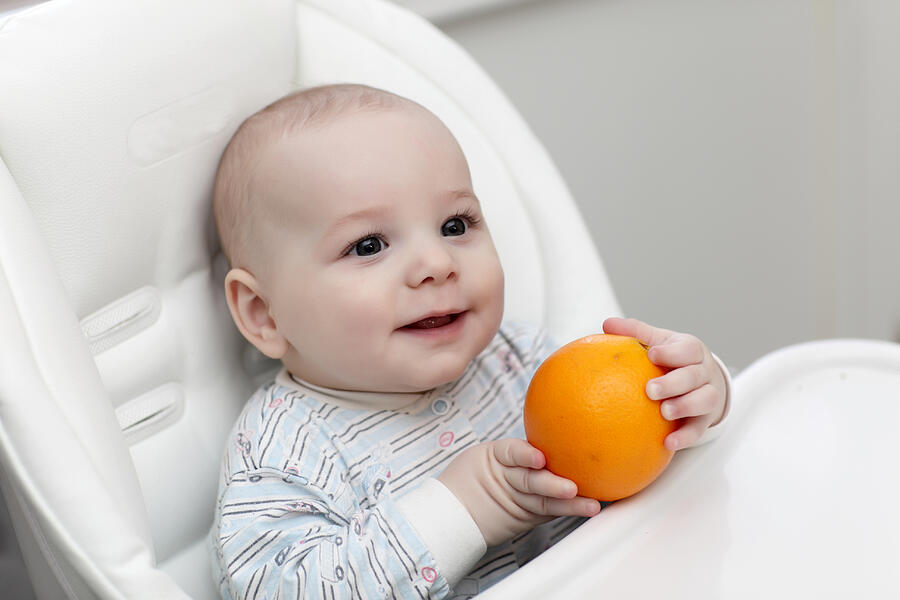 Happy baby with orange Photograph by Radist