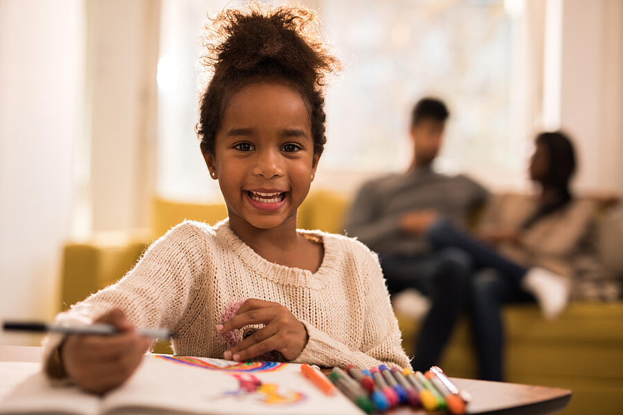 Happy black girl having fun while drawing and looking at camera. Photograph by Skynesher