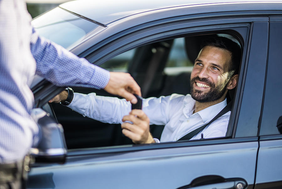Happy businessman receiving keys of his new car. Photograph by Skynesher