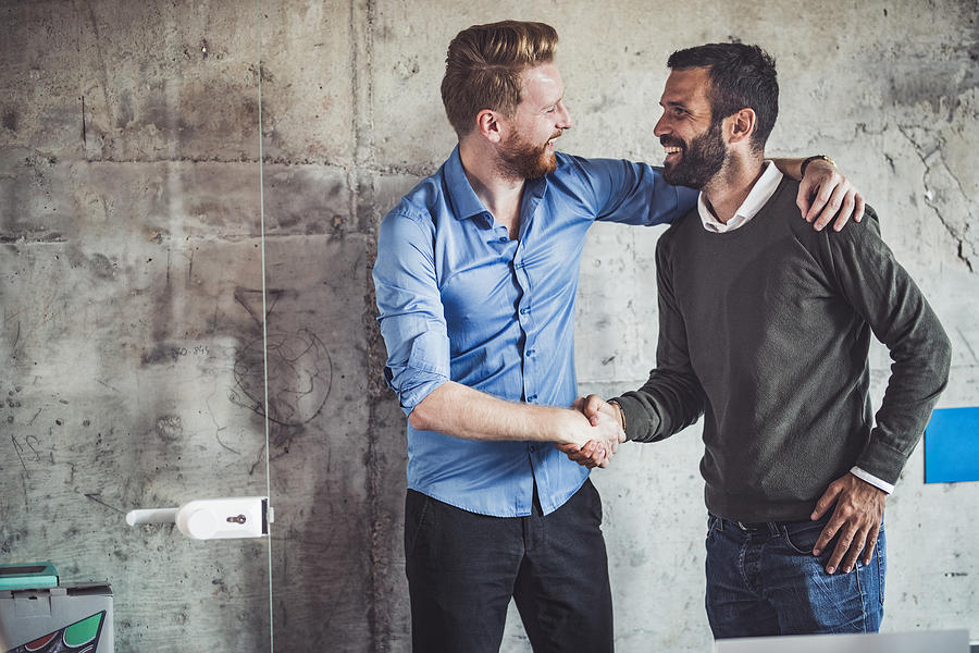 Happy businessmen greeting each other in the office. Photograph by Skynesher