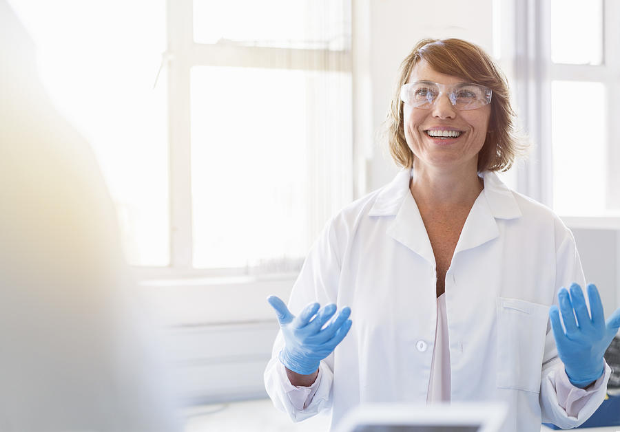 Happy chemist gesturing and talking in laboratory Photograph by Portra