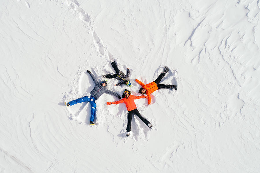 Happy family lying on back on snow Photograph by Miljko