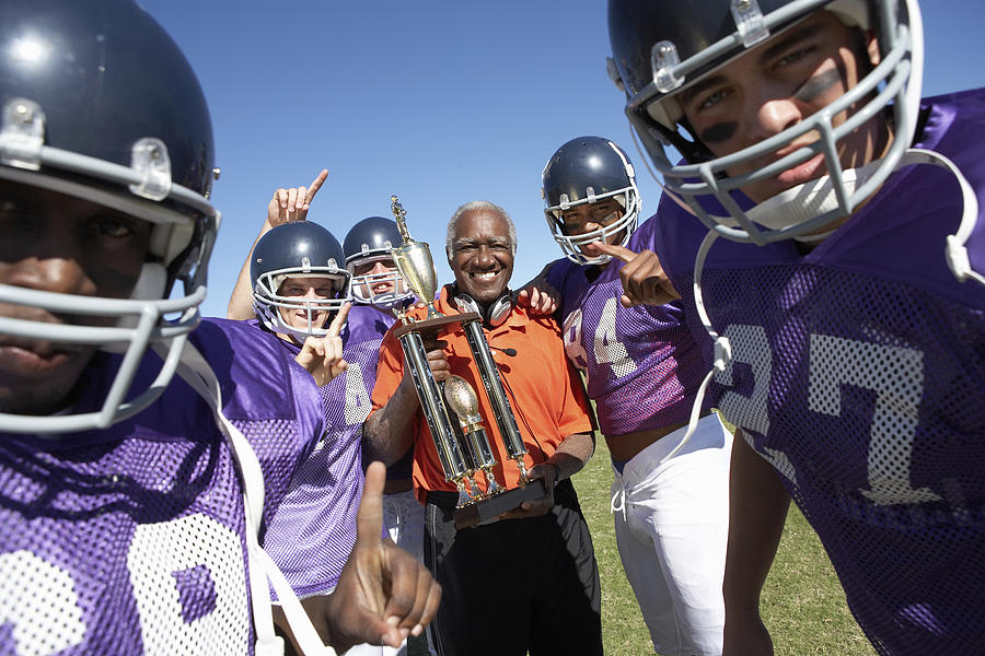 Happy Football Coach with Trophy and Players Photograph by Mike Watson Images