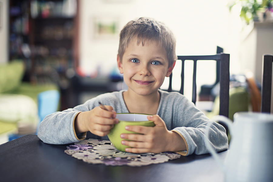 Happy little boy eating breakfast cereal Photograph by Imgorthand