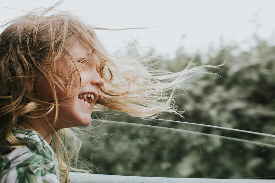 Happy little girl beside an open car window as her hair blows in the wind Photograph by Catherine Falls Commercial