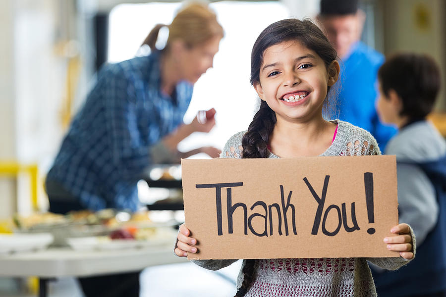 Happy little girl holding THANK YOU sign in food bank Photograph by SDI Productions