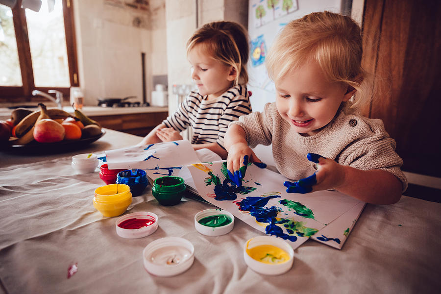 Happy little girls drawing with paint in family house kitchen Photograph by Wundervisuals
