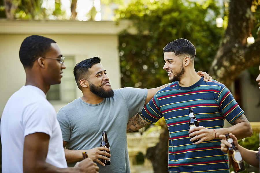 Happy male friends enjoying beer at backyard party Photograph by Morsa Images