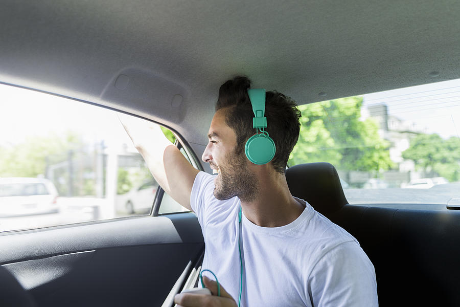 Happy man listening to music on headphones in car Photograph by Portra