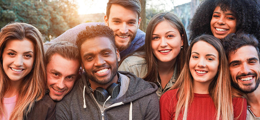 Happy millennial friends from diverse cultures and races having fun posing in front of smartphone camera - Youth and friendship concept - Young multiracial people smiling - Main focus on african man Photograph by DisobeyArt