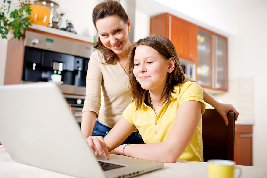 Happy Mother with Daughter using Laptop at home Photograph by Anouchka