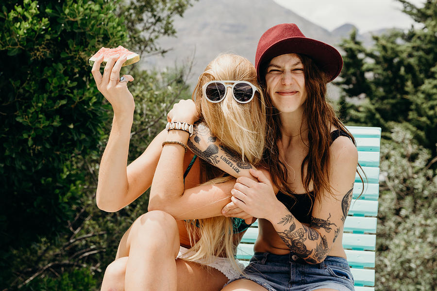 Happy oddball girlfriends embrace outdoors with watermelon in hand Photograph by Hello World