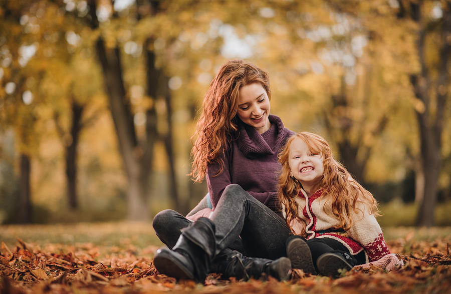 Happy redhead mother and daughter relaxing in the park. Photograph by Skynesher