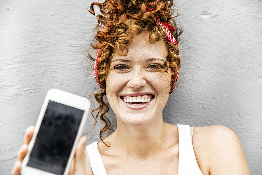 Happy redheaded woman showing cell phone Photograph by Westend61