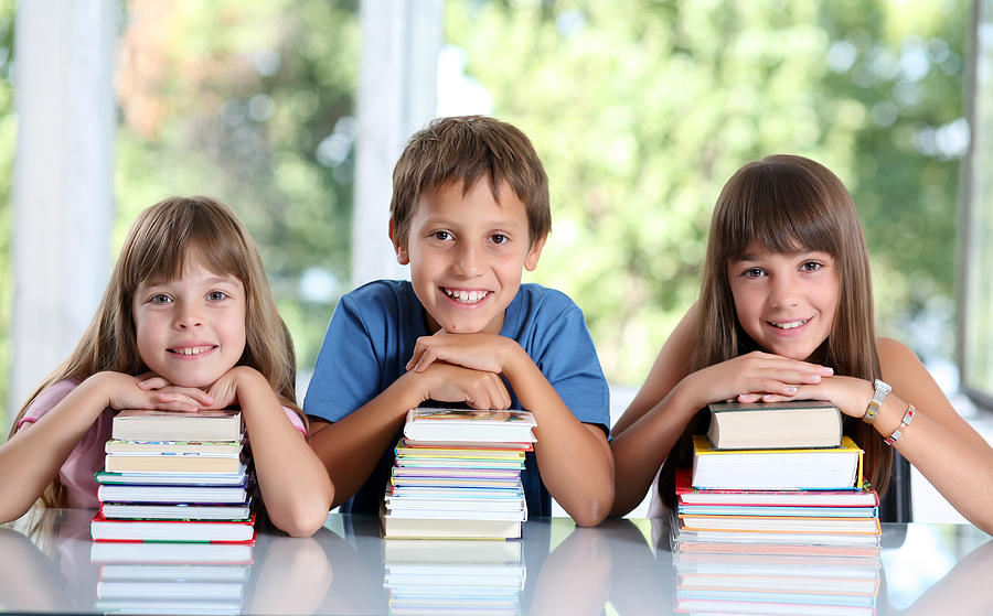 Happy schoolchildren with many books. Photograph by Skynesher