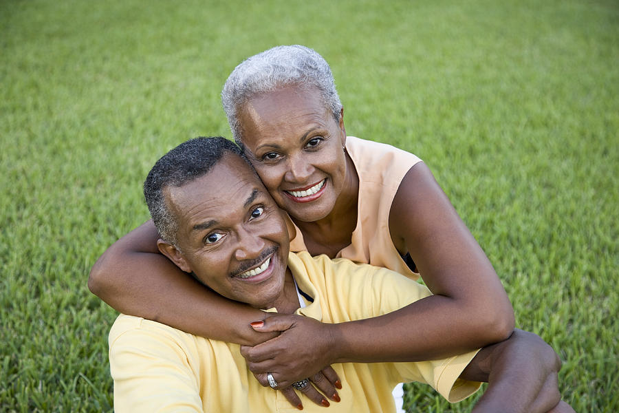 Happy senior African American couple sitting on grass together Photograph by Kali9