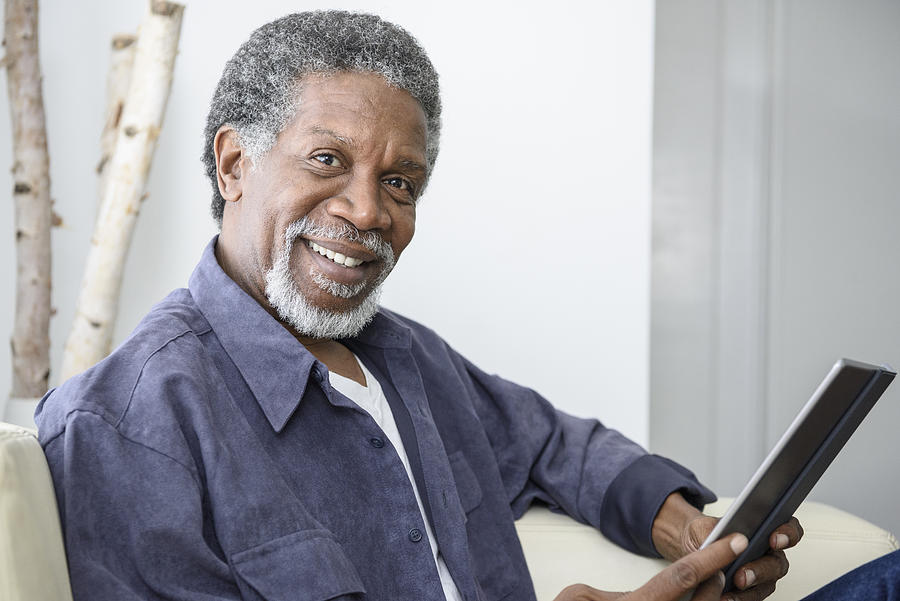 Happy senior African American man with tablet, looking at camera Photograph by JohnnyGreig