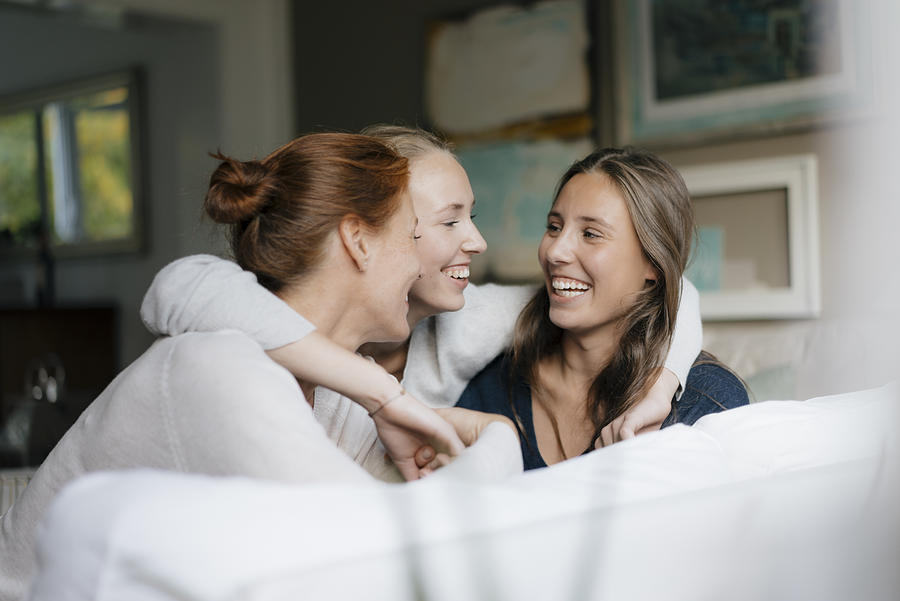 Happy teenage girl hugging mother and sister on couch at home Photograph by Westend61