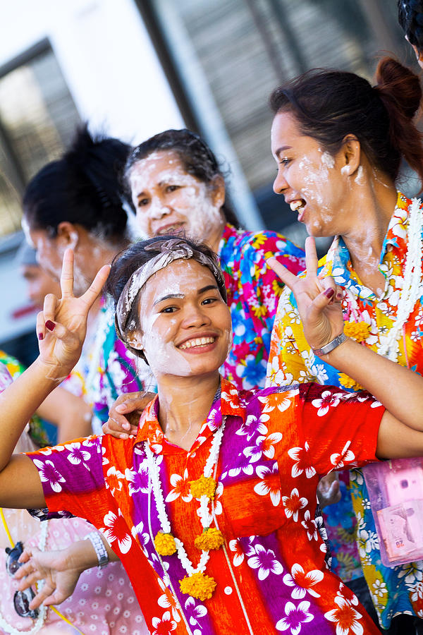 Happy thai women in colored shirts with flowers at Songkran Photograph by Justhavealook
