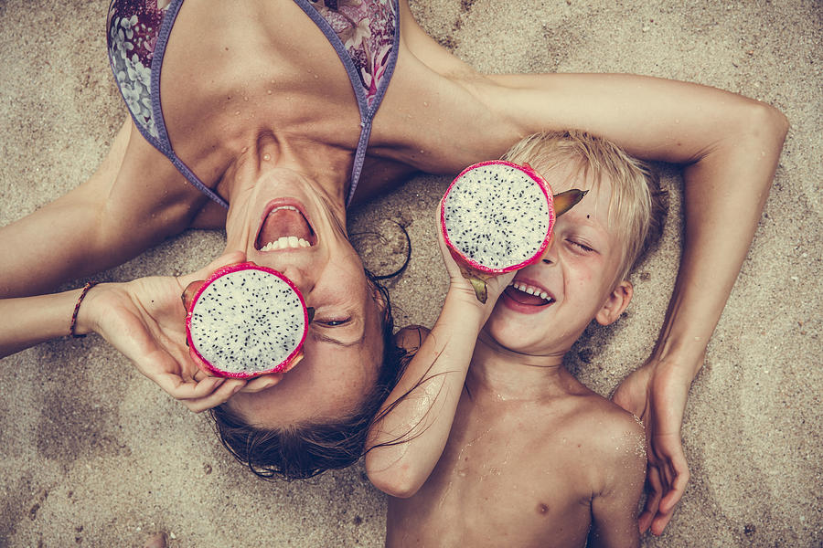 Happy  woman  and boy puts dragon fruit as glasses. Photograph by Neoblues