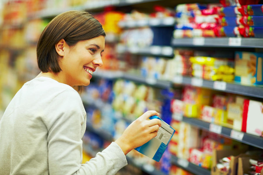 Happy woman choosing products in a supermarket Photograph by GlobalStock