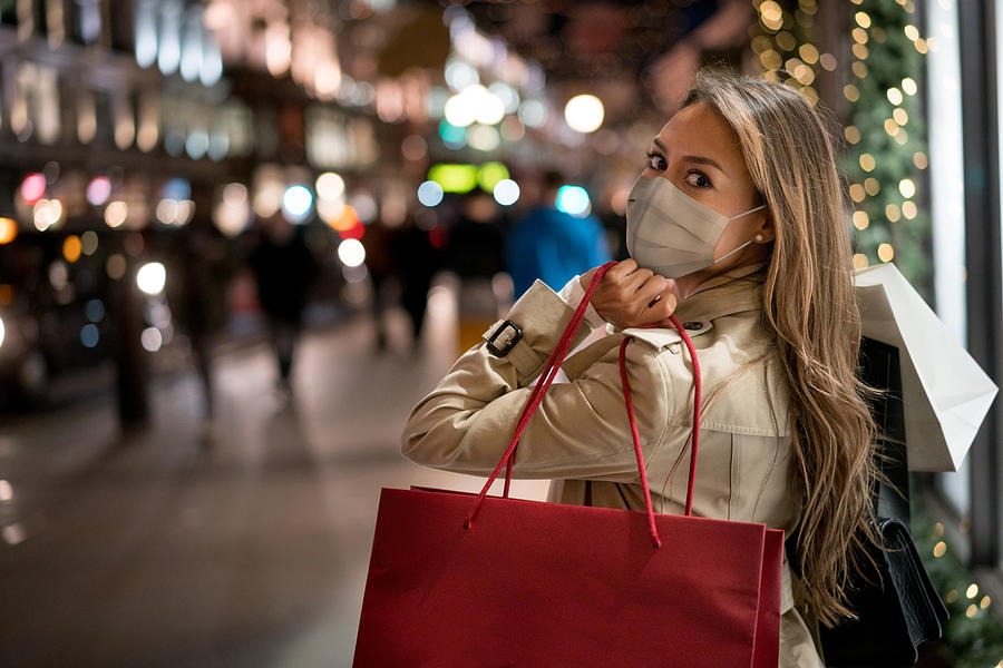Happy woman Christmas shopping wearing a facemask Photograph by Andresr