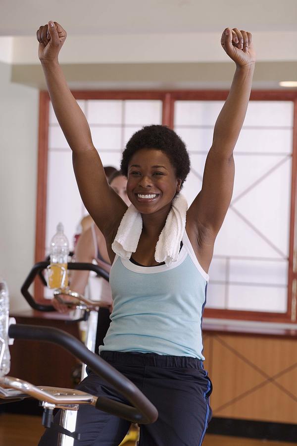 Happy woman with arms raised in exercise class Photograph by Jupiterimages