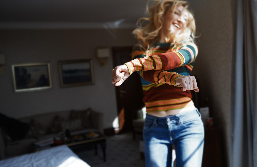 Happy woman with long hair jumping and dancing at home Photograph by Arman Zhenikeyev