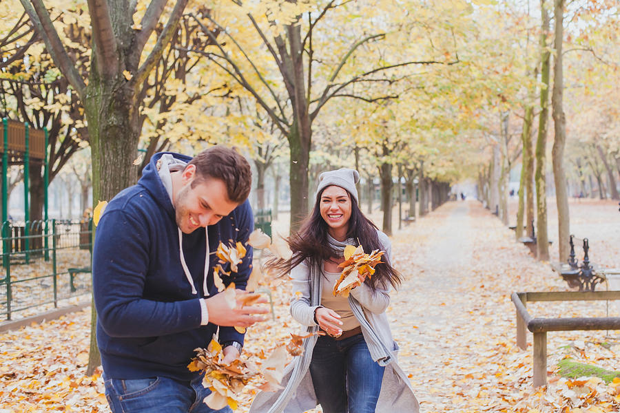 Happy Young Couple Playing In Autumn Park Photograph by Anyaberkut