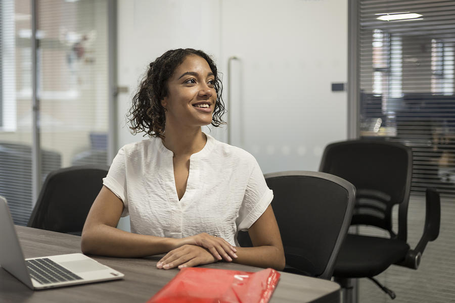 Happy young woman watching a presentation in a modern office Photograph by Kelvinjay