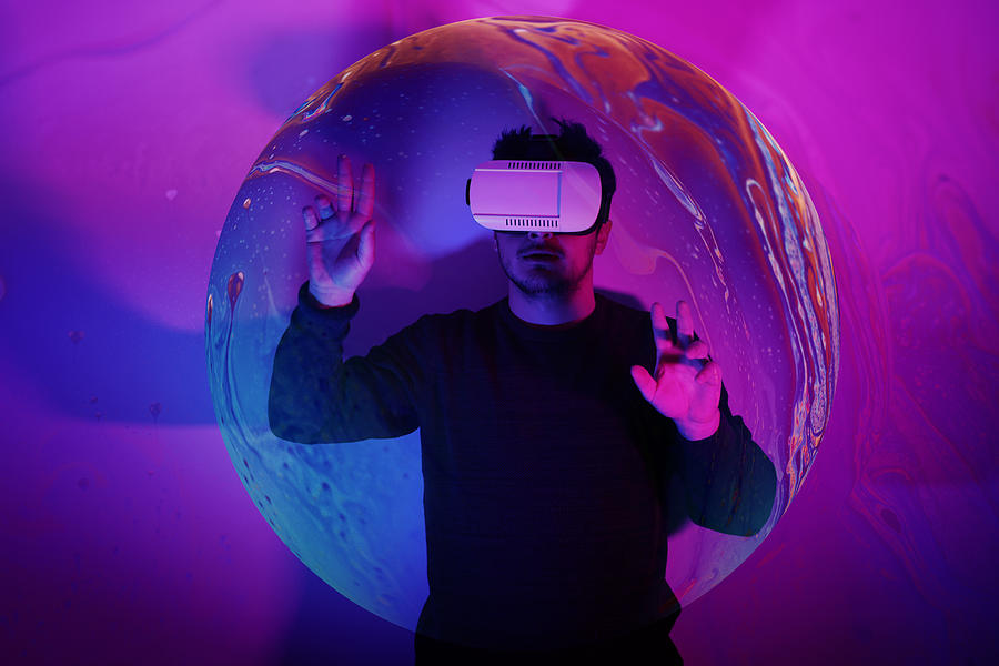 He is discovering metaverse by using VR glasses under neon lights Photograph by Tolgart