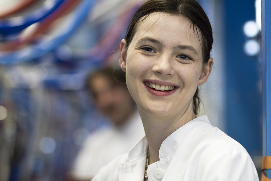 Head and shoulders of your woman wearing lab coat looking at camera smiling Photograph by Sigrid Gombert