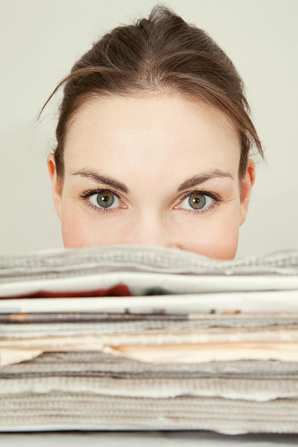 Head shot of young woman looking over the top of a stack of newspapers Photograph by JamieB