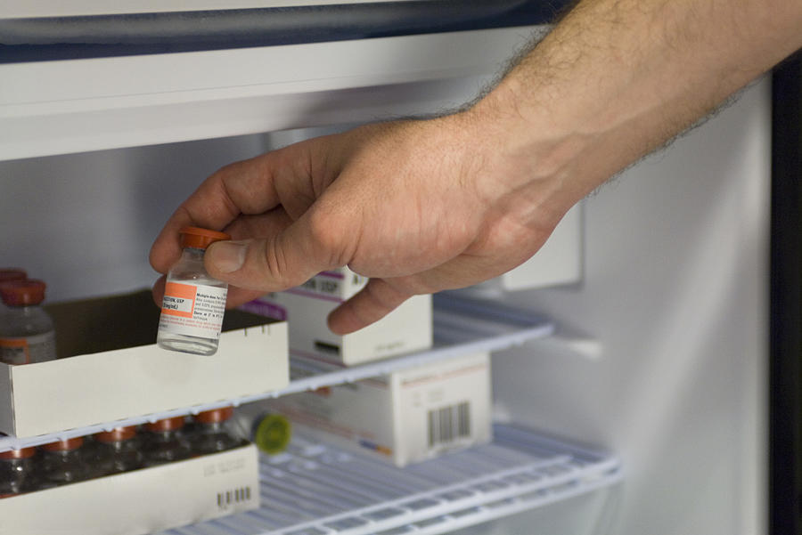 Healthcare professional removing vial of medication from refrigerator Photograph by PhotoAlto/Laurence Mouton