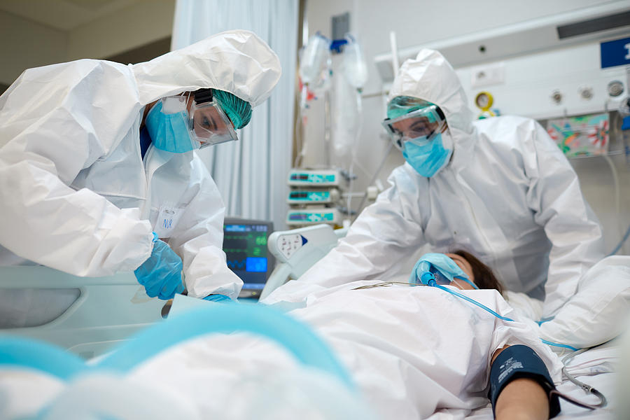 Healthcare workers adjusting equipment to a COVID patient. Photograph by Tempura