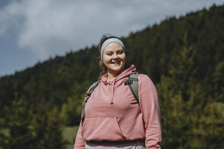 Healthy and Active Lifestyle: Portrait of a Beautiful Happy Plus Size Woman in a Pink Sweatshirt Hiking With a Backpack on her Back Photograph by FreshSplash