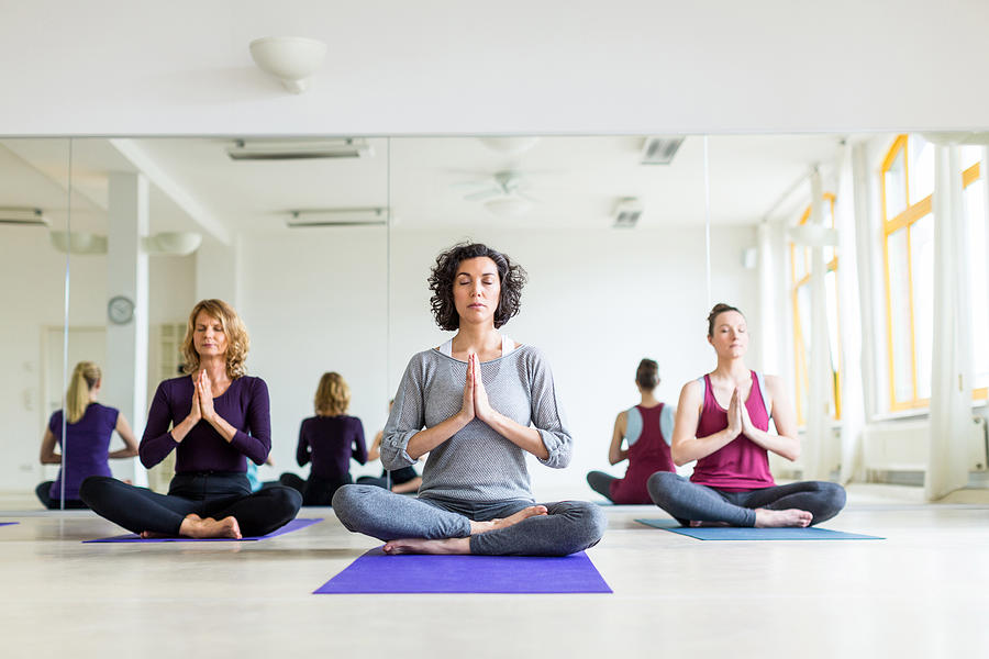 Healthy group of females meditating in yoga pose in gym Photograph by Alvarez