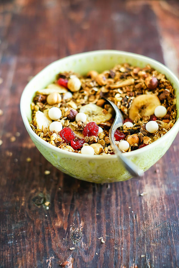 Healthy homemade granola or muesli with toasted oats, dried cherry, cranberry, figs, raisin, hazelnuts, cashew, walnuts, white chocolate chips in a bowl for breakfast or snack, selective focus Photograph by Anna Kurzaeva