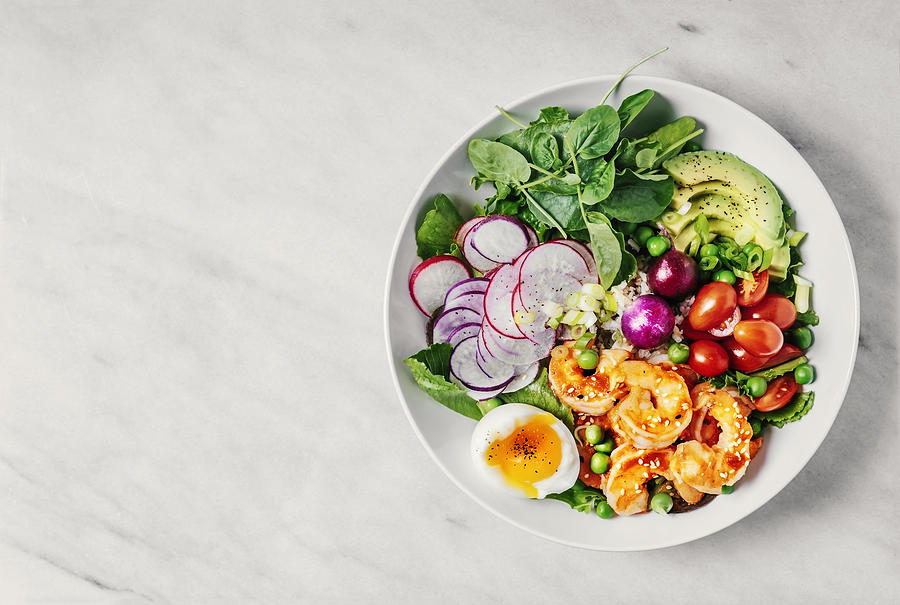 Healthy lunch bowl with greens, avocado, cherry tomatoes, radish, boiled egg, and shrimp on white background Photograph by Claudia Totir